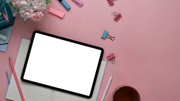 Obere Ansicht des modernen femininen Arbeitsplatzes mit digitalem Tablet, Stift, Schreibwaren, Notizbuch und Kopierraum auf rosa Hintergrund. - Foto, Bild