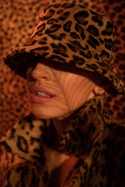 Woman hiding her eyes under the fields of her leopard panama while posing - Zdjęcie, obraz