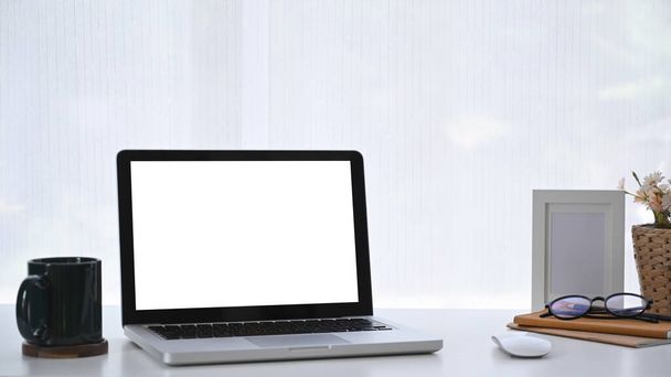 Cómodo lugar de trabajo con ordenador portátil, taza de café y portátil en el escritorio blanco. - Foto, Imagen