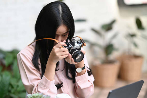 Junge Fotografin überprüft Foto vor der Kamera, während sie in ihrer Werkstatt sitzt. - Foto, Bild