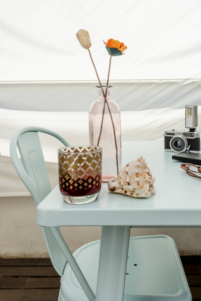 Image relaxante d'une table sur une terrasse penthouse avec une boisson, une coquille de conque, un vase avec des fleurs et un appareil photo vintage - Photo, image