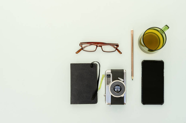Vue du dessus de l'appareil photo vintage avec bloc-notes, lunettes de vue, tasse de thé et smartphone - Photo, image
