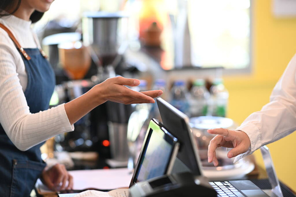 Gehakt shot gastvrije serveerster beveelt haar aan om iets speciaals te bestellen in een coffeeshop. - Foto, afbeelding