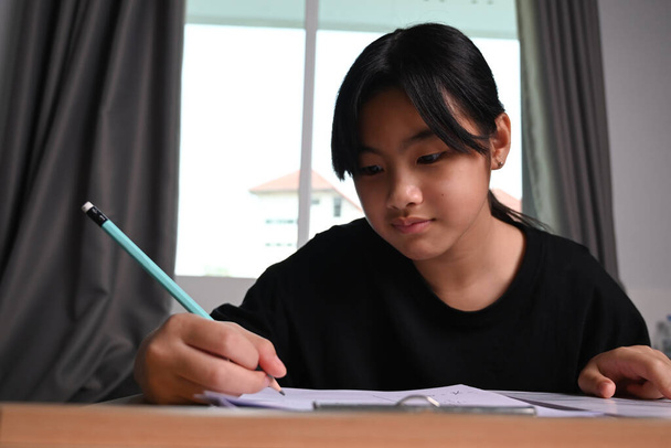 Asian children girl doing homework on wooden desk at home.  - Photo, Image