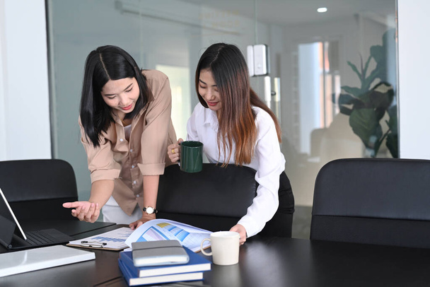 Two young businesswoman reading and analyzing report in office. - Photo, Image