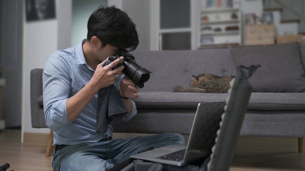 Young man photographer checking and adjusting his camera setting before shooting. - Photo, image
