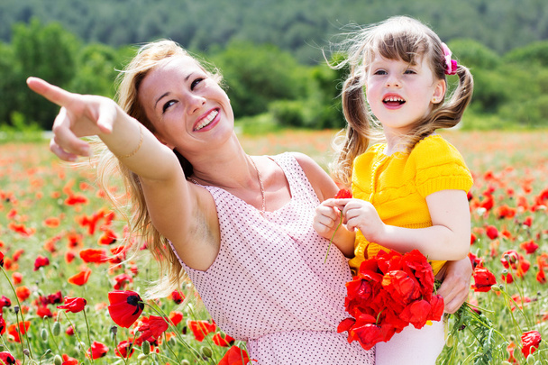 Mother playing with her child in poppy field - Foto, imagen