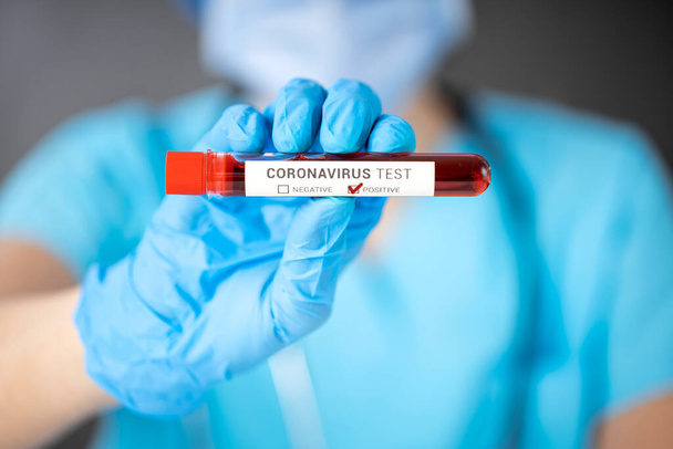 Nurse wearing respirator mask holding a positive blood test result for the COVID-19 - Φωτογραφία, εικόνα
