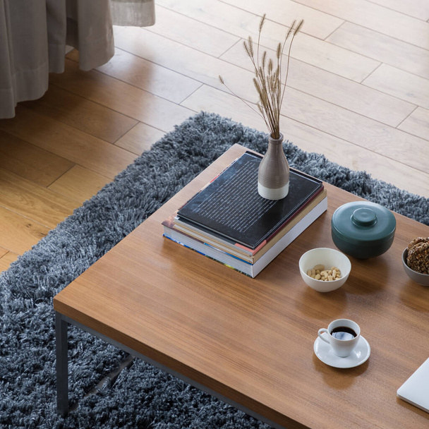 Top view on wooden coffee table with decorations, books, vase, bowls and white cup of coffee - Fotó, kép