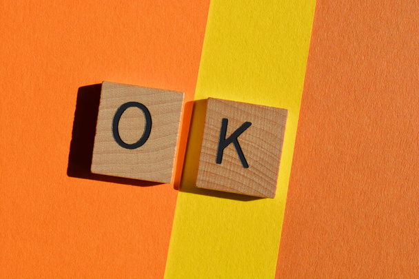 OK, abbreviation for okay, wooden alphabet letters isolated on orange and yellow - Photo, image