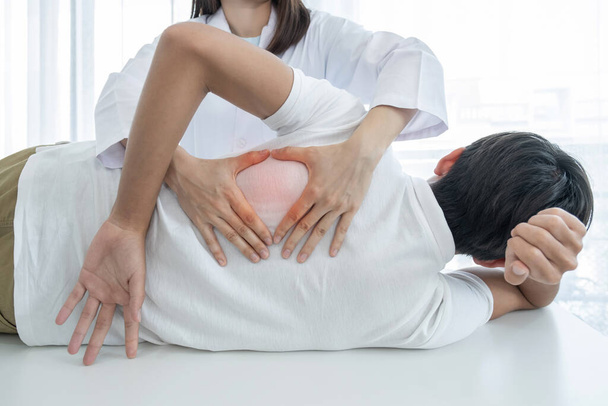 Ärztinnen machen physikalische Therapie, indem sie einem männlichen Patienten den Rücken ausstrecken. - Foto, Bild