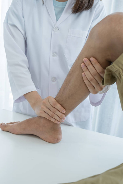 Жіночі руки лікаря роблять фізичну терапію Розширюючи ногу і коліно пацієнта чоловічої статі
. - Фото, зображення