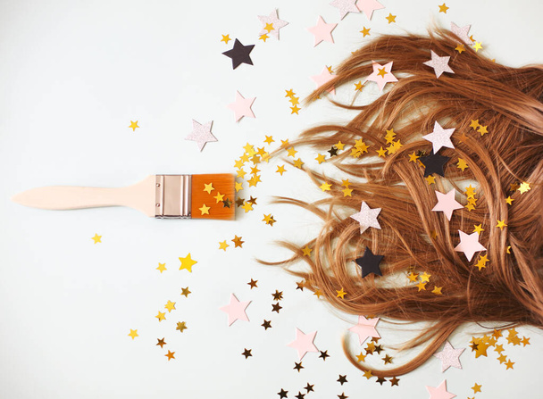 From above of soft silky hair on white background with brush aside all in scattered star shaped confetti - Photo, Image
