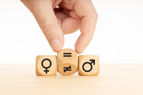 Gleichstellungskonzept. Hand dreht einen Holzblock um und verwandelt ein ungleiches Zeichen in ein gleiches Zeichen zwischen Symbolen von Männern und Frauen - Foto, Bild