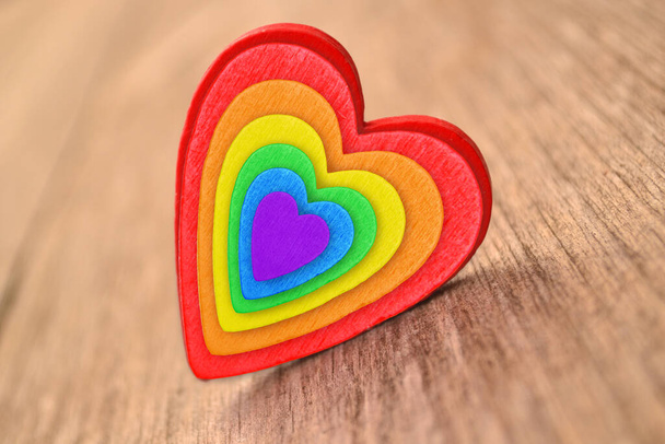 Icon in the form of a rainbow LGBT heart on a wooden background.The concept of equality of sexual minorities for a postcard, poster or banner of activists.Rainbow Flag Day - Foto, immagini