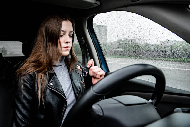 Молода жінка закріплює ремінь безпеки перед водінням автомобіля
. - Фото, зображення