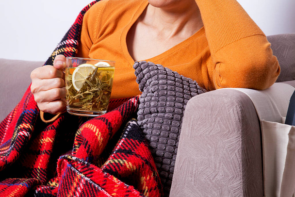 The woman is holding a cup of hot sage. The woman is sick and the weather is cold.  - Photo, Image