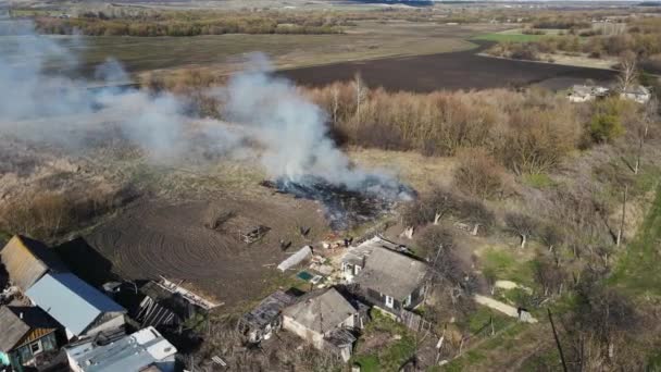 burning grass and debris near residential buildings. aerial shooting. - Video