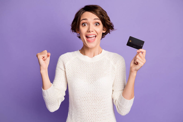 Photo portrait of pretty girl holding plastic bank card gesturing like winner isolated on bright purple color background - Photo, Image