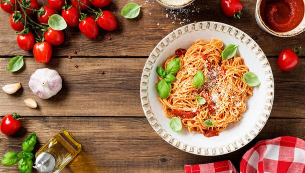 おいしいトマトソースと古典的なイタリアのスパゲティパスタ、パルメザンチーズと新鮮なバジルの葉。木の背景、上の景色 - 写真・画像