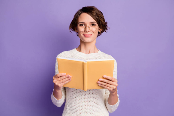 Photo portrait of clever female student smiling with book wearing eyewear isolated on vibrant purple color background - Foto, Bild