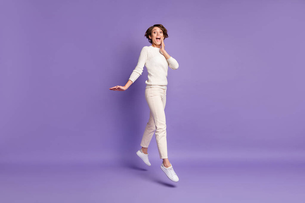 Full length body size photo of happy girl bob hair jumping touching cheek smiling isolated on pastel purple color background - Zdjęcie, obraz