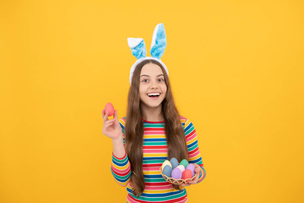 великодній. час для розваги. чарівна смішна дитина на полюванні на яйце. Великоднє весняне свято. щаслива дівчина-підліток носить вуха кролика. щасливого Великодня. щастя дитинства. дитина в кролячих вухах тримає пофарбовані яйця
. - Фото, зображення