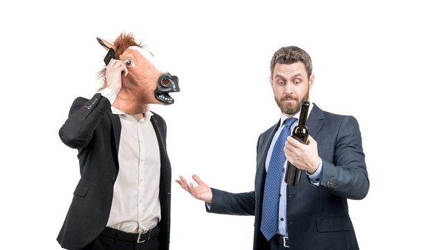 Hombre extraño en la máscara de caballo hablar en el teléfono móvil mientras gerente beber vino celebrando fiesta corporativa aislado en blanco, celebración. - Foto, imagen
