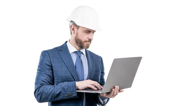 confident businessman man in suit and safety helmet wotking on laptop online isolated on white, work online. - 写真・画像