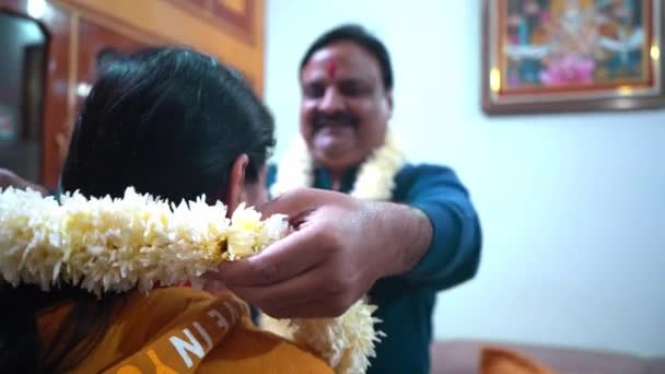 gelukkig indiaanse vrouw zetten op een witte bloemenslinger naar haar man thuis in Agra, India - Medium schot, Slow Motion - Video