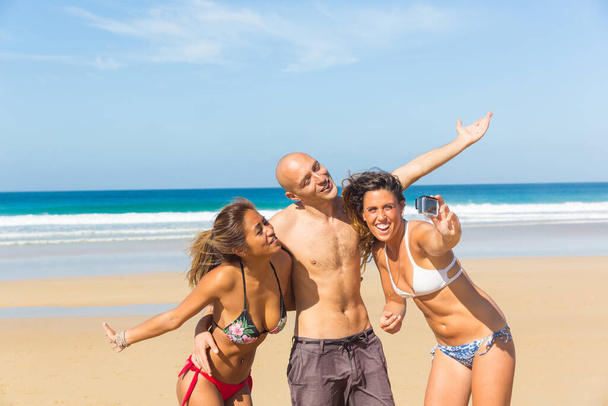 Happy multiracial friends taking a selfie at seaside - Multiethnic people having fun together in sunny Fuerteventura - Man and women at beach enjoying time together - Foto, Bild