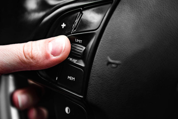 Hand pushes cruise control button on steering wheel and speed limitation. - Foto, immagini
