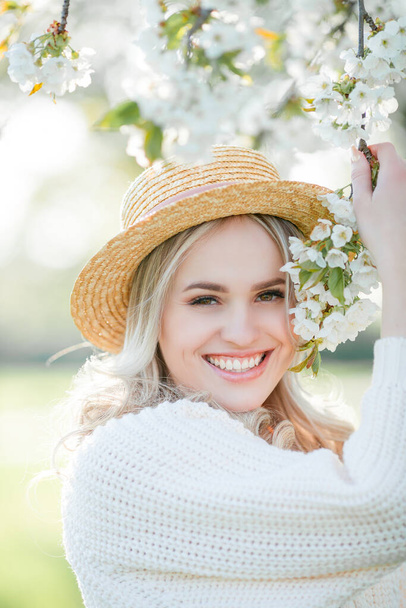 Belle jeune femme se repose sur un pique-nique dans un jardin fleuri. Fleurs blanches. Printemps. - Photo, image