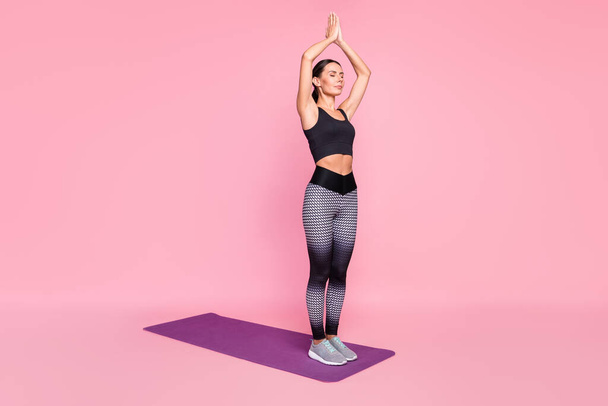 Photo of sweet peaceful young woman dressed sportive outfit practicing yoga closed eyes isolated pink color background - Fotografie, Obrázek