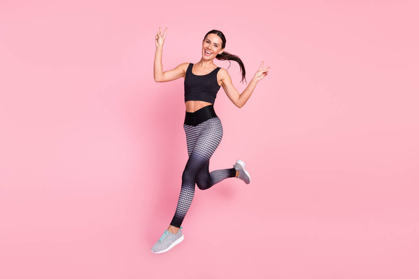 Volledig lichaam profiel zijkant foto van jonge sportieve vrouw gelukkig glimlach run springen show vrede cool v-teken geïsoleerd over pastel kleur achtergrond - Foto, afbeelding