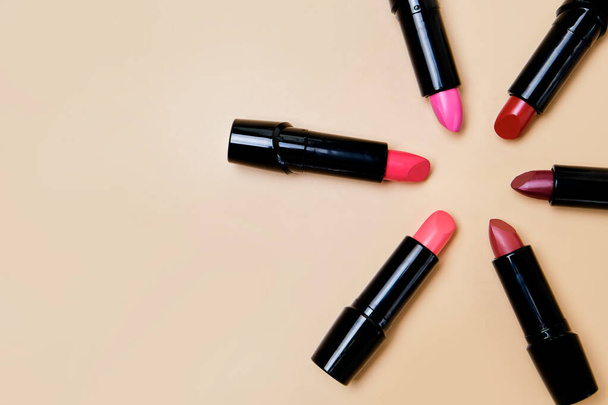 Flat lay composition with lipsticks and space for text on beige background. Open lipsticks without caps close up - Foto, afbeelding