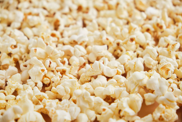 Yellow movie style popcorn background. Lots of spilled popcorn, texture. - Photo, Image