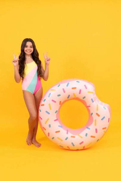 summer vacation. happy girl in swimsuit inflatable doughnut ring. teen with swimming ring. child hold beach accessory of inflatable circle. active childhood. summertime kid weekend. sunbathing. - Fotografie, Obrázek