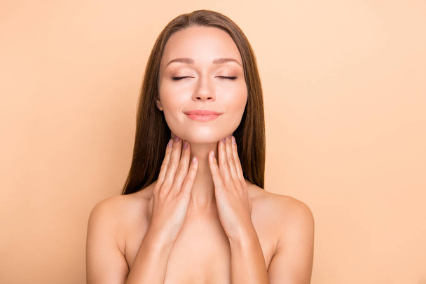 Photo of pretty happy lady closed eyes arms touch neck applying cosmetic no clothing isolated on beige color background - Φωτογραφία, εικόνα