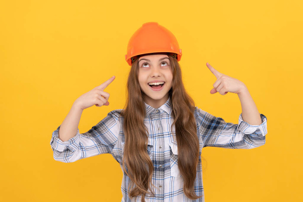 feliz adolescente menina apontando dedo no capacete na camisa quadriculada, proteção. - Foto, Imagem