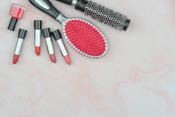 Mujer concepto de accesorios, lápiz labial rojo, cepillo en la superficie de mármol rosa. Composición adecuada para cosméticos publicitarios, espacio de copia vacío para texto - Foto, imagen