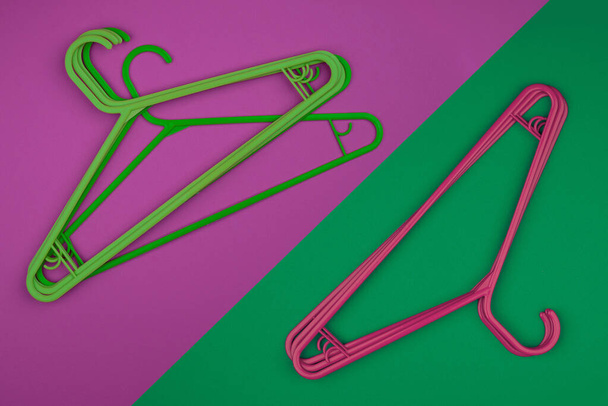 Üres ruhafogas, sokszínű műanyag vállfák. Bolt és szekrény rózsaszín és zöld kiegészítők. Divatos vásárlási fényes koncepció - Fotó, kép