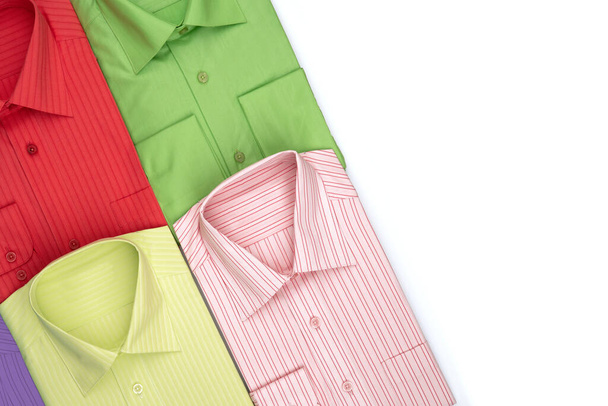 Egy új ing egy bolt vagy raktár ablakában. Uniszex sokszínű ruhák. Értékesítés, kedvezmények, előléptetés koncepció. Piros, zöld, rózsaszín, sárga színek - Fotó, kép