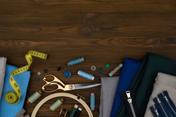 Knippen en naaien aangepaste kleding, naaien accessoires. Schaar, draden, stoffen op een houten tafel. Lege kopieerruimte - Foto, afbeelding