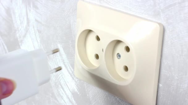 Caucasian woman hands switch on the white power plug usb charger into the electrical socket close up - Footage, Video