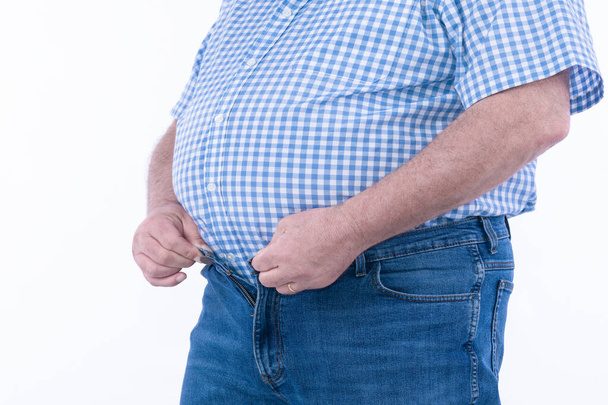 Man met overgewicht die probeert te kleine kleren op een witte achtergrond te bevestigen: Selectieve focus - Foto, afbeelding
