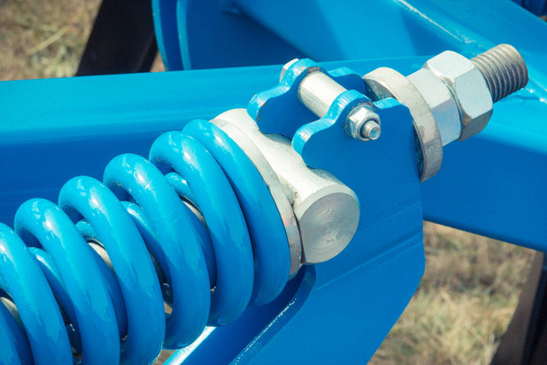 Hard blue spring made of steel. Part and detail of industrial or agricultural machine. Technology - Foto, immagini