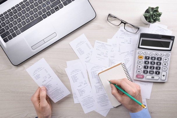 Unrecognizable businessman using calculator on desk office and writing make note with calculate about cost at home office. finance accounting concept. tax , shopping, cost management. - 写真・画像