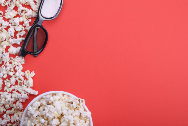 3D-s szemüveg és popcorn vörös háttérrel. Felülnézet. - Fotó, kép