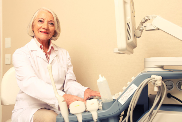 Счастливая взрослая женщина-врач с помощью ультразвукового сканера. Эхография
  - Фото, изображение